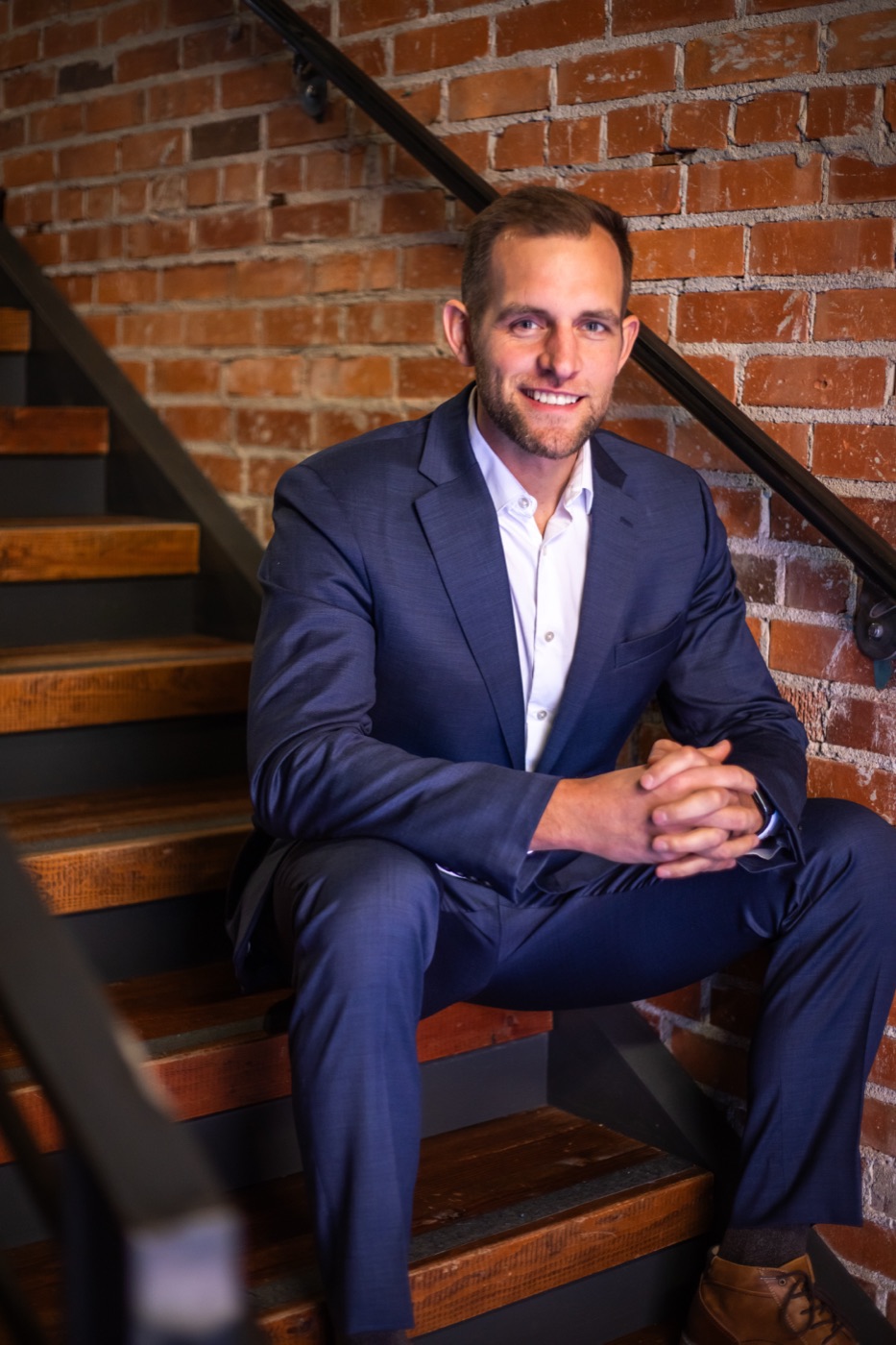 Chris Kiefer sitting on a brick stairway in a navy suit